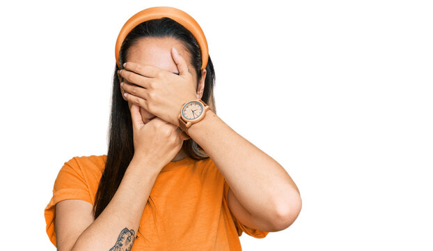 Young hispanic woman wearing casual clothes covering eyes and mouth with hands, surprised and shocked. hiding emotion
