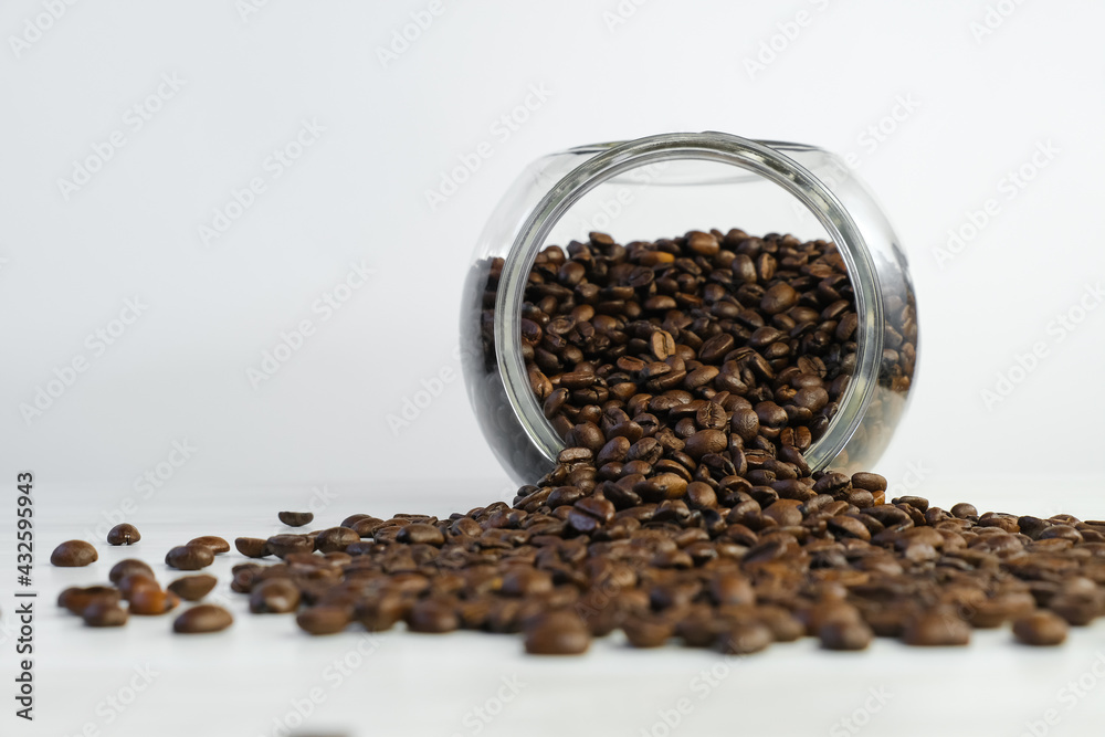 Wall mural glass jar with roasted coffee beans on white table. coffee beans in a coffee shop ready for grinding