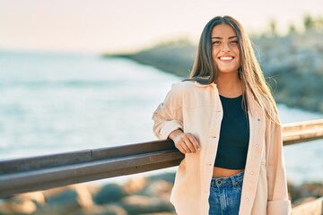 Young hispanic girl smiling happy leaning on the balustrade.