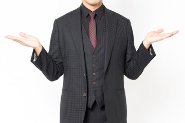 白背景の前に立って、案内のジェスチャーをする男性ビジネスマン