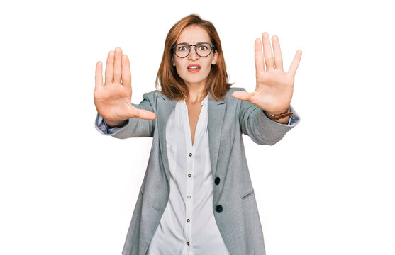 Young caucasian woman wearing business style and glasses doing stop gesture with hands palms, angry and frustration expression