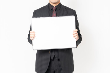 白背景の前に立って、大きいスケッチブックを持つ男性ビジネスマン - obrazy, fototapety, plakaty