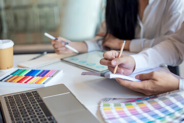Close-up of a designer hand holding a pen working with a color sample at the office.