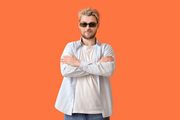 Young man with stylish sunglasses on color background