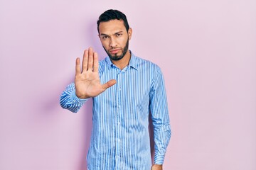 Hispanic man with beard wearing casual blue shirt doing stop sing with palm of the hand. warning...