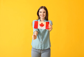 Beautiful young woman with the flag of Canada on color background