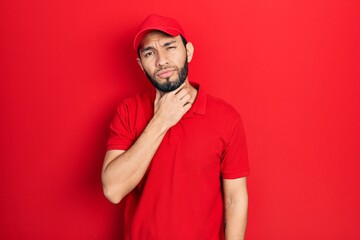Hispanic man with beard wearing delivery uniform and cap touching painful neck, sore throat for flu, clod and infection