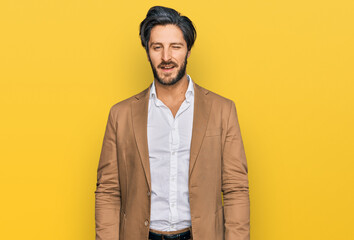 Young hispanic man wearing business clothes winking looking at the camera with sexy expression,...