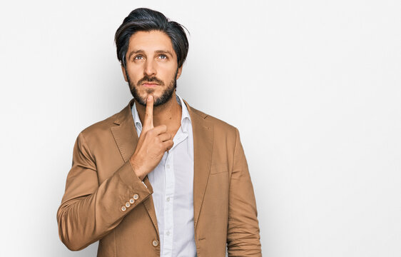 Young hispanic man wearing business clothes thinking concentrated about doubt with finger on chin and looking up wondering
