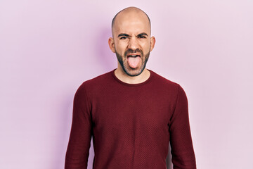 Fototapeta premium Young bald man wearing casual clothes sticking tongue out happy with funny expression. emotion concept.