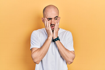 Young bald man wearing casual white t shirt tired hands covering face, depression and sadness, upset and irritated for problem