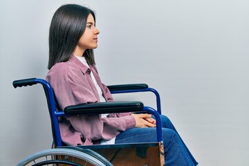 Young brunette woman sitting on wheelchair looking to side, relax profile pose with natural face...