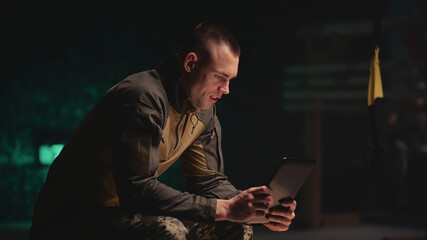 Military man making video call in dark gym