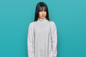 Young brunette woman with bangs wearing casual turtleneck sweater skeptic and nervous, frowning...