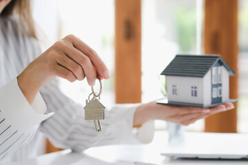 Hands holding house model and key on table for finance and banking concept.Home purchase mortgage...