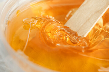 Sugar paste or wax honey in a transparent jar on a white background. Sugaring. Depilation and...