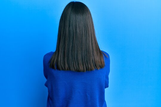 Young asian woman wearing casual winter sweater standing backwards looking away with crossed arms