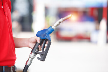 hand of man holding pump nozzle for service at gas station. male employee worker fueling oil car. business energy concept.