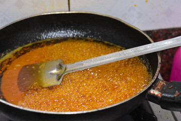 Simmering golden sugar syrup, steel spatula