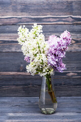Bouquet of lilac flowers in a vase on a wooden table