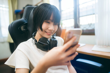 Young adult asian woman wear headphone using smart phone for social online content.