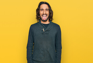 Young hispanic man wearing casual clothes sticking tongue out happy with funny expression. emotion concept.