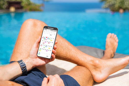 Man sitting by the pool and using calendar app on his phone