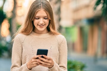 Beautiful caucasian teenager smiling happy using smartphone at the city.