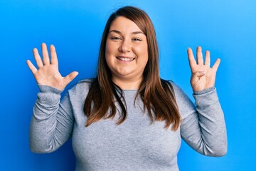 Beautiful brunette plus size woman wearing casual clothes showing and pointing up with fingers...