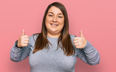 Beautiful brunette plus size woman wearing casual clothes success sign doing positive gesture with hand, thumbs up smiling and happy. cheerful expression and winner gesture.