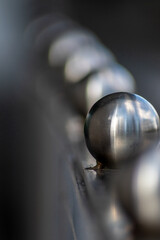 Matt steel balls in a row as decorative and ornamental balustrade and futuristic fence design with a lot of copy space, a selective focus and a blurred background for metal industry metal architecture