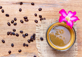 iop view of a cup of black americano coffee on a sackcloth wooden table with a pile of organic brown coffee beans. Morning refreshment concept