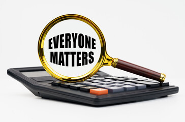 On a white background lies a calculator and a magnifying glass with the inscription - Everyone Matters
