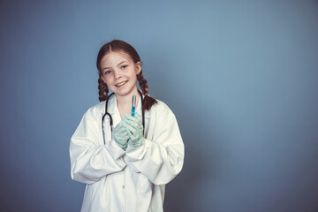 beautiful, cool young girl dressed as female doctor with stethoscope and syringe and rubber gloves posing in front of blue background