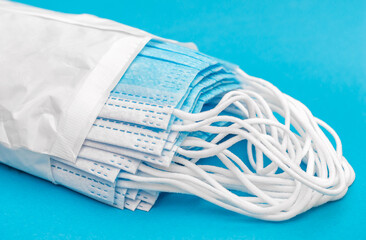 Opened pack of medical masks on blue.