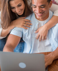 Close up of young couple working on laptop at home - happy people enjoy online computer and connection together with fun and happiness - love and life - interracial relationship man and woman