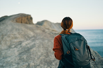 beautiful woman hiker with a backpack on her back in the mountains near the sea landscape model