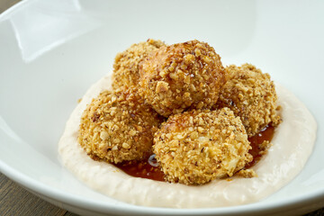 A traditional dish of Ukrainian cuisine is Gombovtsy or Baoji. Sweet balls of semolina and plum jam with white sauce. served in a white plate on a wooden background