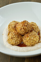 A traditional dish of Ukrainian cuisine is Gombovtsy or Baoji. Sweet balls of semolina and plum jam with white sauce. served in a white plate on a wooden background