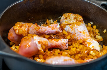 Chicken legs with roasted onion in the iron pan. Dinner or lunch cooking, detail view.