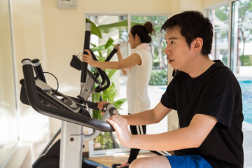 Happy young Asian couple work out in gym - obrazy, fototapety, plakaty