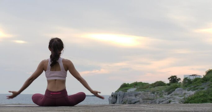 Happy young woman relaxing by practicing yoga on the beach at sunset, Sunrise background. Fitness, sport, yoga and healthy lifestyle concept. 