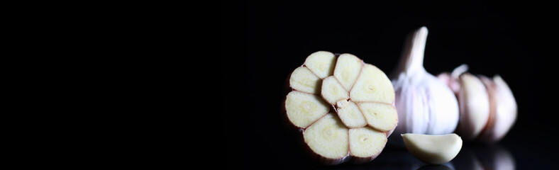Fresh garlic clove on black background. Garlic is rich in vitamins, useful spring, good spices. Garlic sliced on a dark background. Raw sliced garlic.