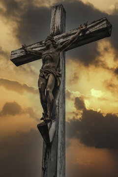 Vertical shot of a crucifix with cloudy sky at sunset in the background