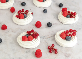 Meringues or mini Pavlova. Sweet dessert decorated with different berries. Fresh baking concept. Selective focus.