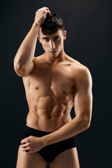 Fototapeta premium handsome athletic man in dark shorts posing dark background