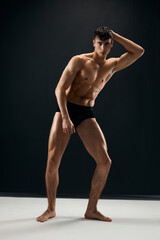 Naklejka premium sporty man with muscular naked body in black panties on a dark background