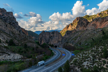 Refrigerated truck driving on a road between rocky mountains.