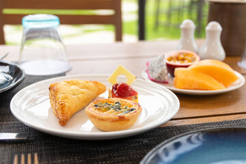 Spinach quiche, Pie and Cheesecake mini snack set on white plate in a garden.