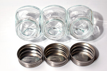 Three empty glass jars with scattered lids. Isolate